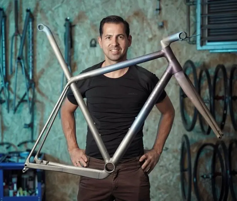 Dennis holding a titanium road frame in the workshop